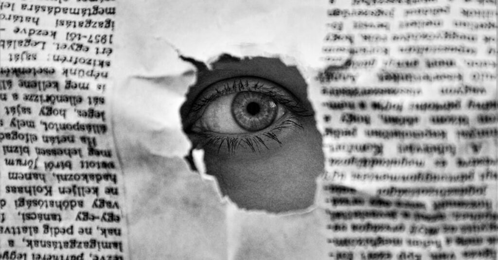 A mysterious eye peering through a hole in a black and white newspaper, creating an intriguing visual.